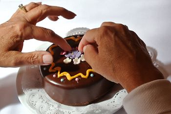 Two hands decorating a Sacher cake