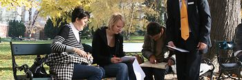 A group of people sitting in the park and solving a puzzle